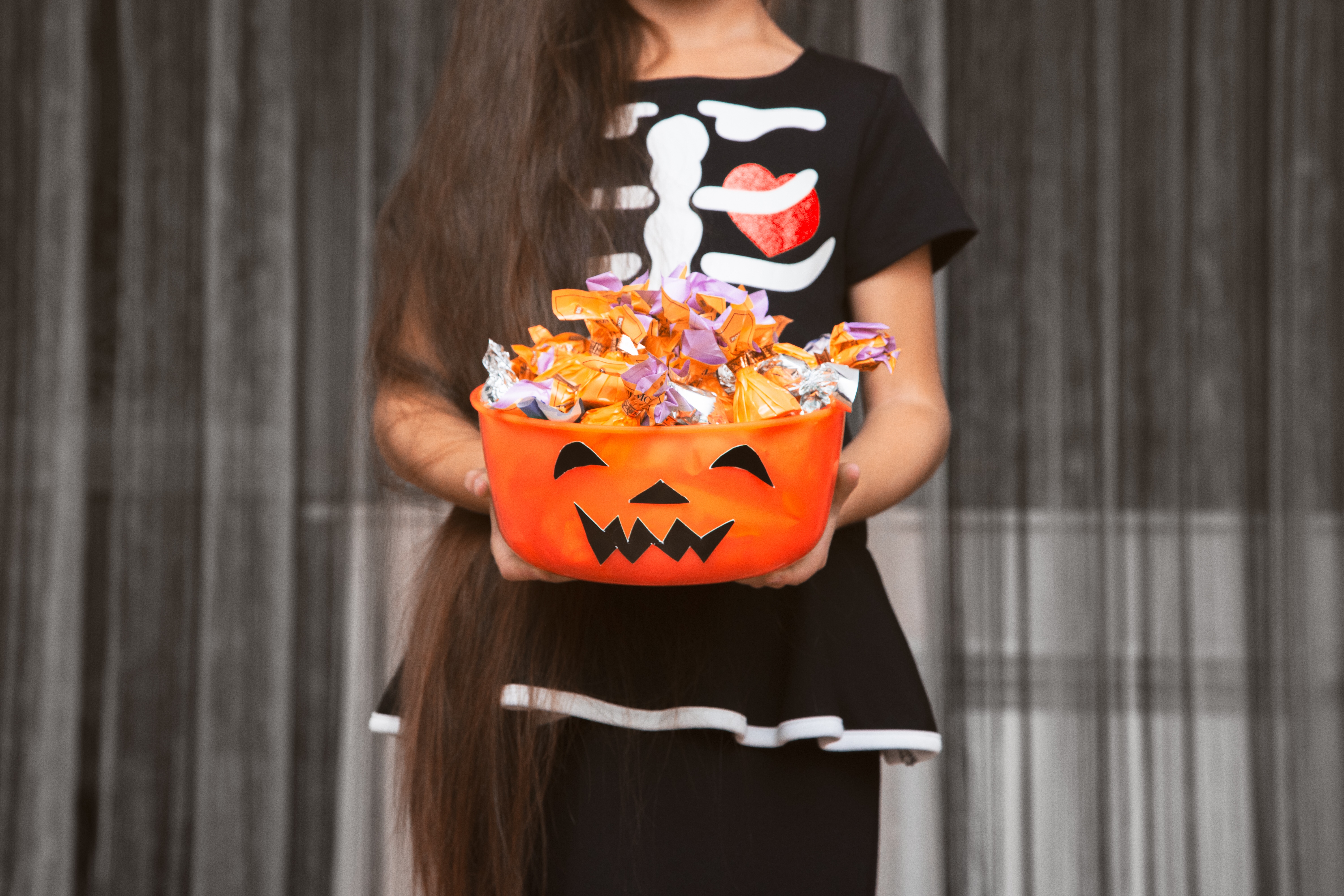 Little girl is holding a scary bowl with candies