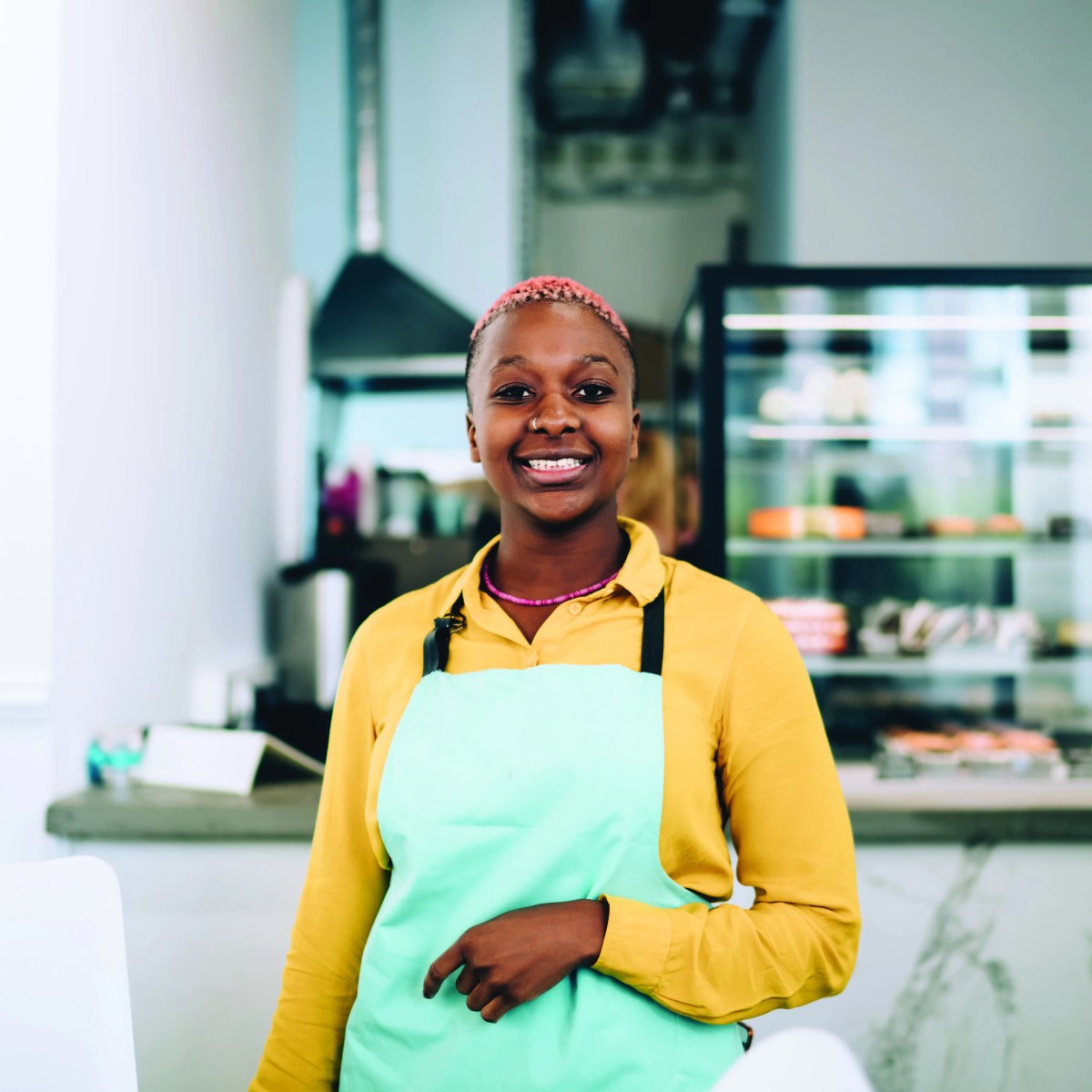 Person in apron smiling while working in a cafe