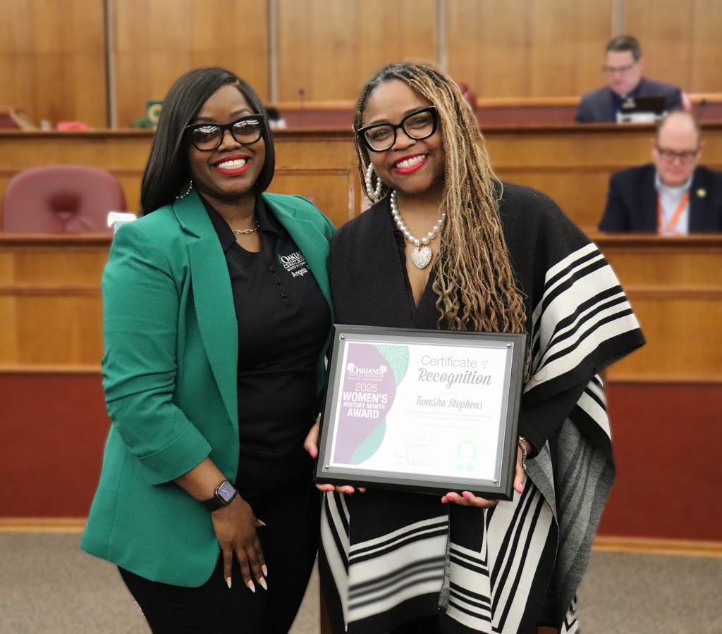 Two women stand together with a plaque.
