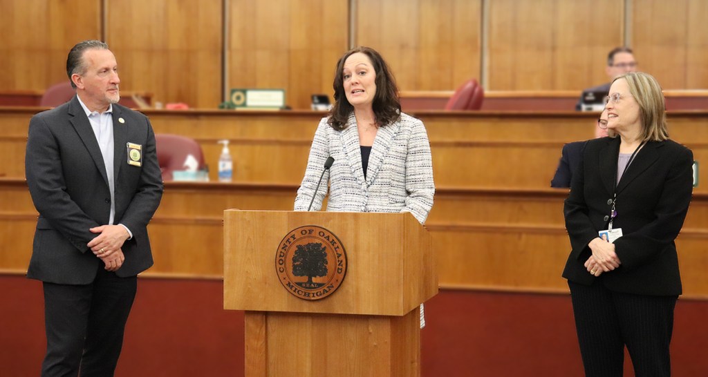 A man and two women stand at a podium.